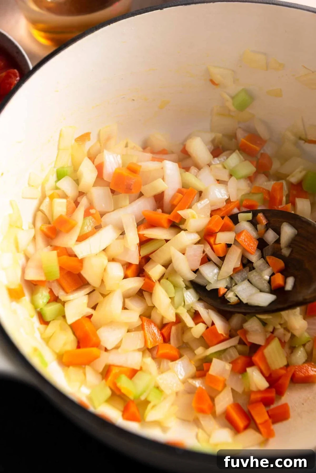 Carrot, onion, celery and garlic cooking in a soup pot.