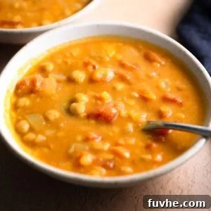 Bowl of creamy lentil chickpea soup with a spoon in it.