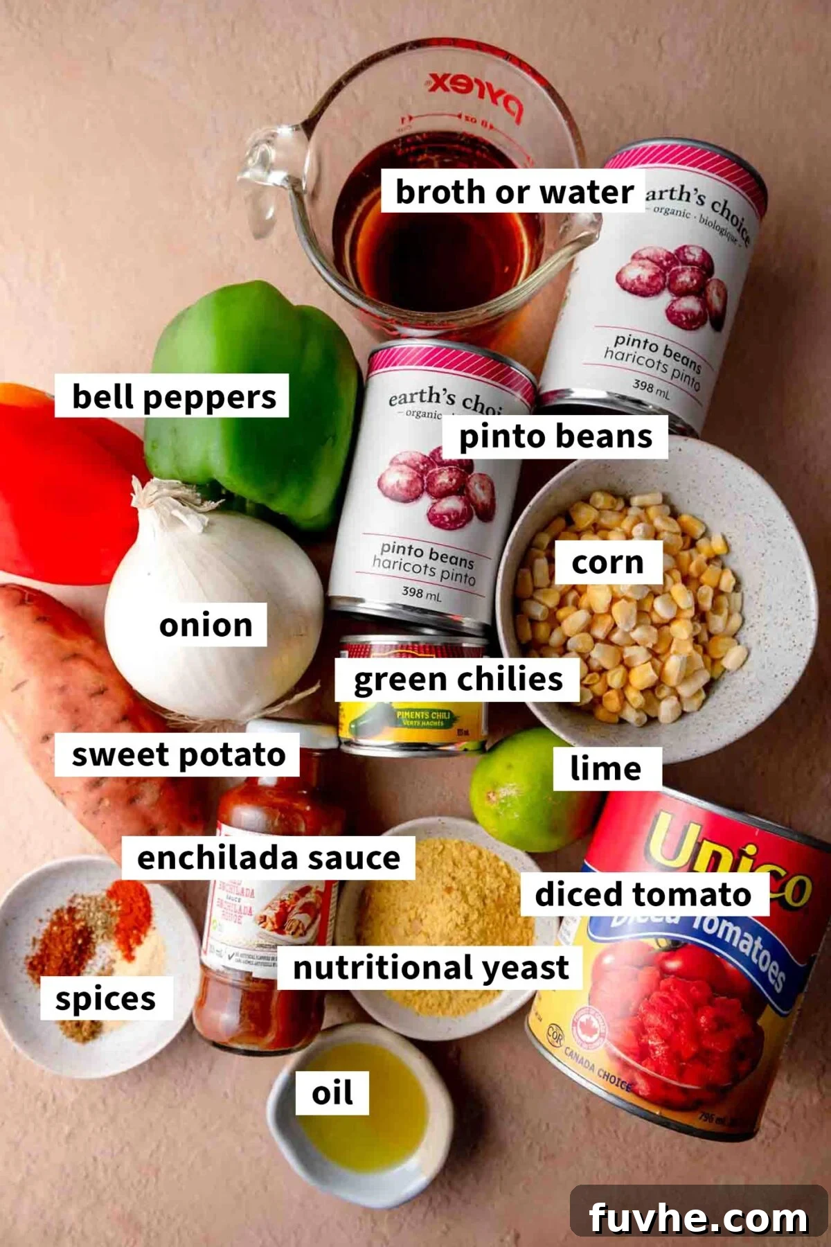 Ultimate Vegan Enchilada Soup 3 A vibrant flat lay showcasing all the fresh and canned ingredients for a homemade vegan enchilada soup, including pinto beans, sweet potato, bell peppers, diced tomatoes, enchilada sauce, green chilies, nutritional yeast, and various spices.