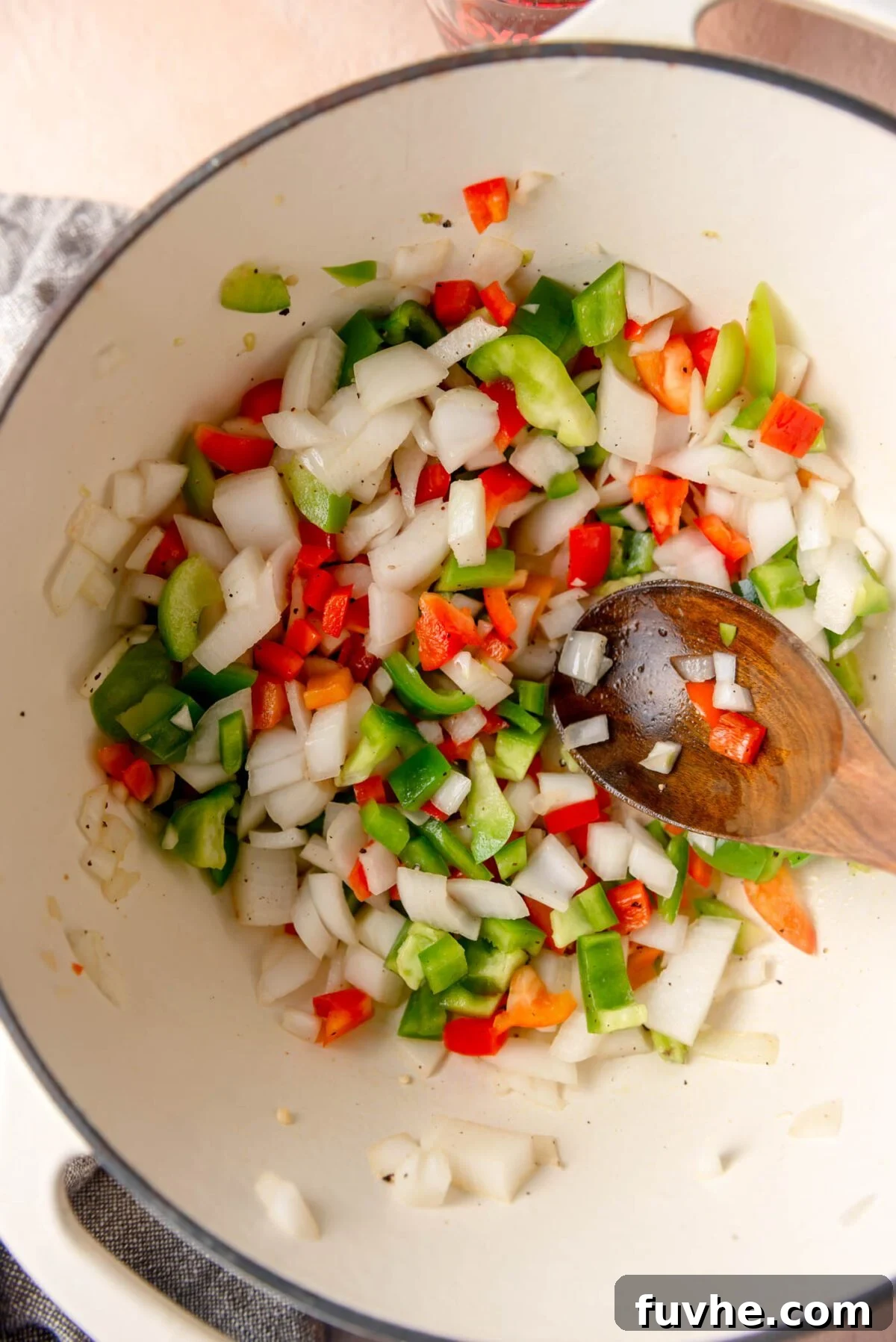 Ultimate Vegan Enchilada Soup 4 Diced white onion and colorful bell peppers sautéing in a large pot on the stove, creating an aromatic base for the soup.
