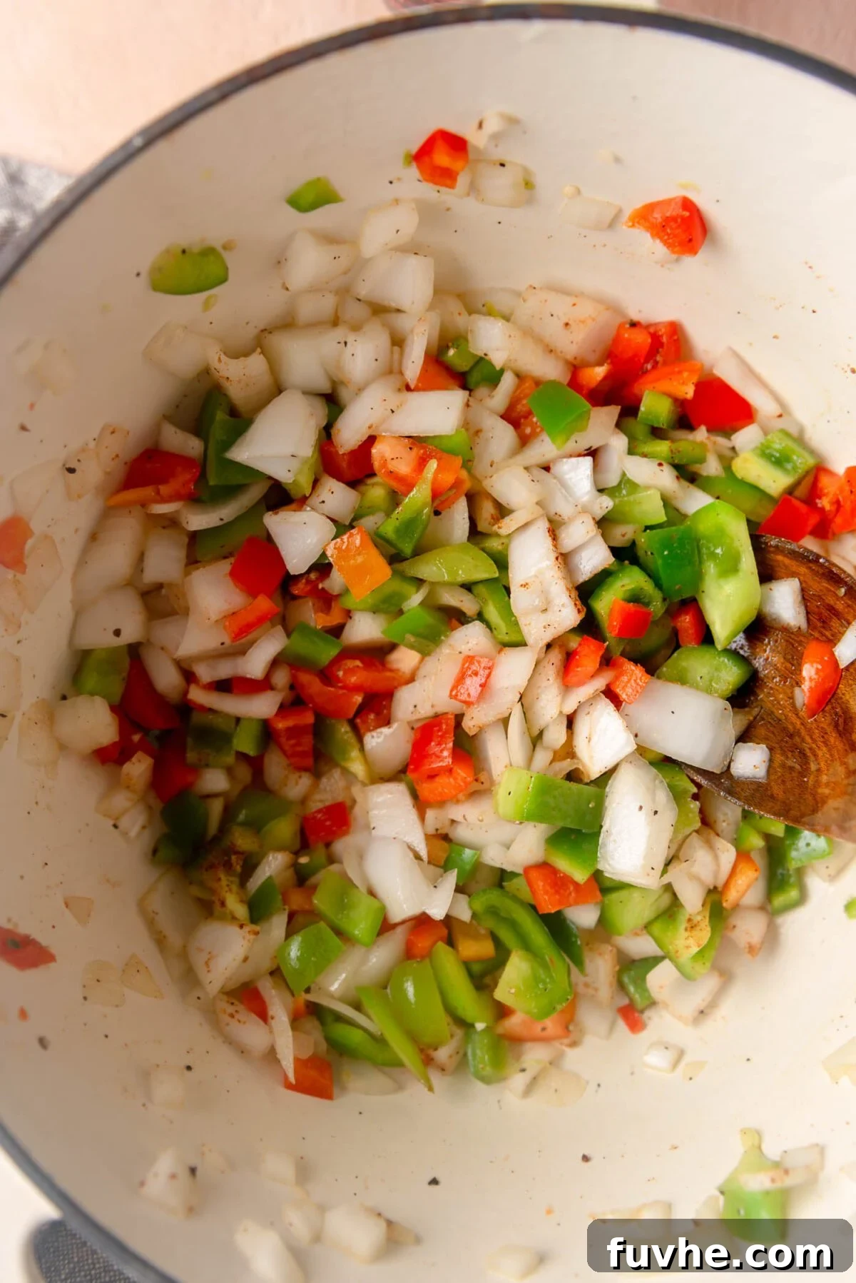 Ultimate Vegan Enchilada Soup 5 Fragrant chili powder, cumin, garlic powder, oregano, and smoked paprika being stirred into sautéed onions and bell peppers in a large soup pot.