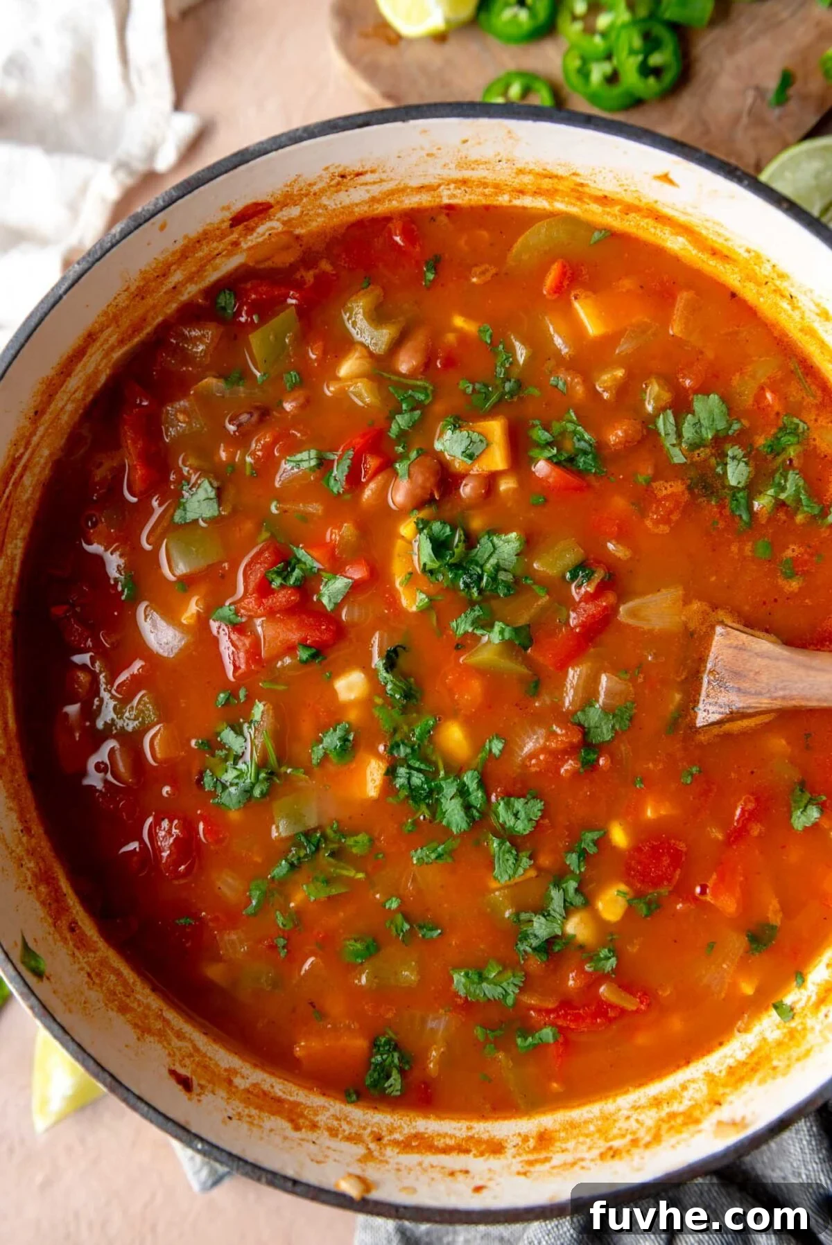 Ultimate Vegan Enchilada Soup 7 A close-up of a large pot of finished vegan enchilada soup, rich in color, with visible chunks of bell pepper, sweet potato, and pinto beans, garnished with fresh cilantro.