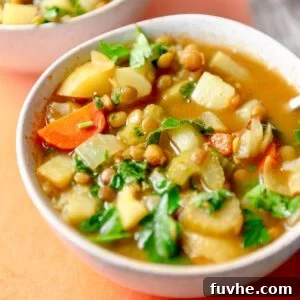 Bowl of a hearty soup with potatoes, carrots, lentils and kale.