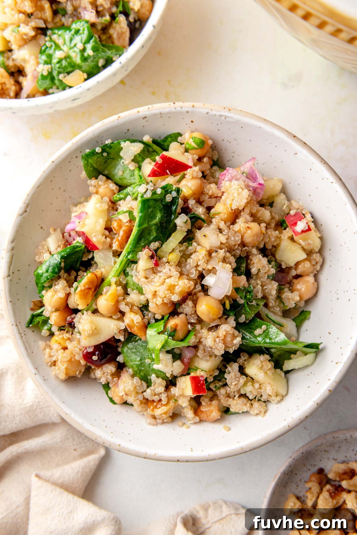 Crisp Apple Quinoa Salad 2 Vibrant bowl of Apple Quinoa Salad featuring crisp apple pieces, dried cranberries, crunchy walnuts, fresh spinach, and sliced celery, all tossed together in a light dressing.