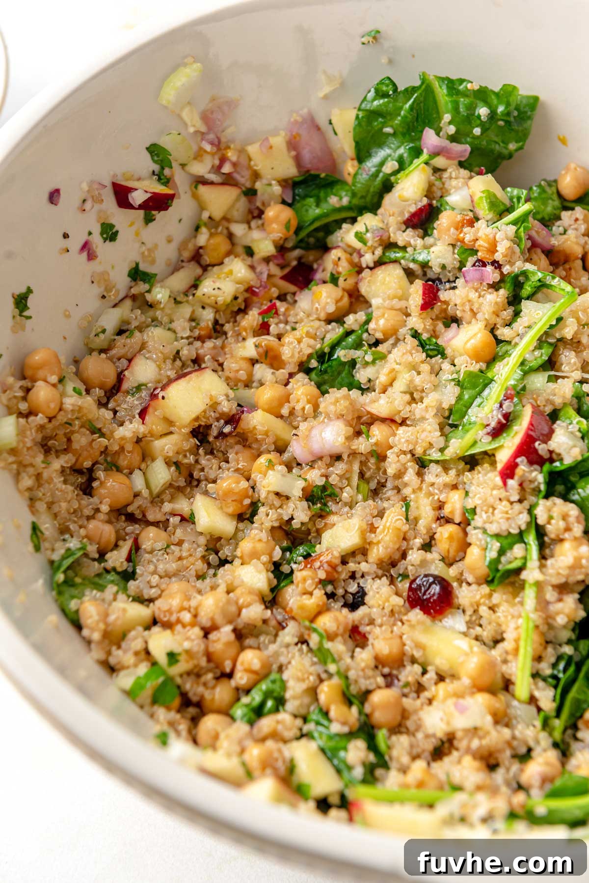 Crisp Apple Quinoa Salad 4 Large mixing bowl filled with vibrant Apple Quinoa Salad, featuring fresh spinach, whole chickpeas, and diced celery, ready to be served.
