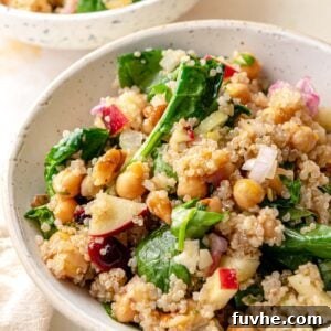 Bowl of quinoa salad with apples, cranberries, walnuts, spinach and celery.