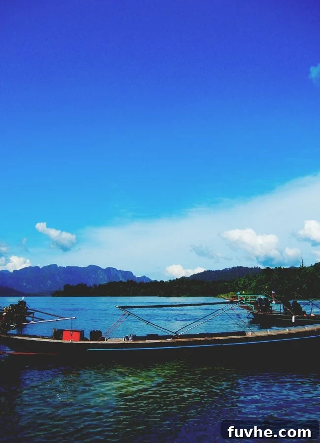 A longtail boat approaches the scenic floating huts in Khao Sok National Park