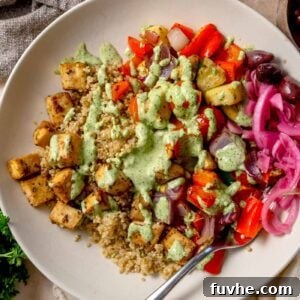 Mediterranean roasted veggie bowl with crispy lemon tofu, quinoa, roasted vegetables, and green tahini sauce.