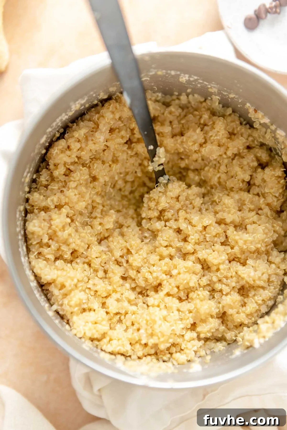 Fluffy cooked quinoa resting in a saucepan with a wooden spoon, ready to be served as a wholesome base for a nutritious meal.