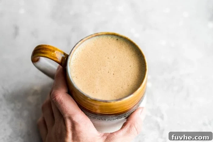A hand grabbing a mug of vegan bulletproof coffee.