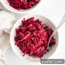 Overhead shot of two bowls of beet, apple and cabbage slaw in bowls, garnished.