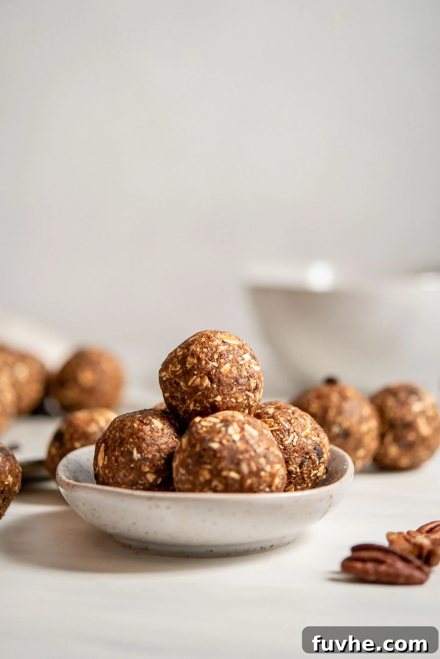 No-Bake Banana Bread Truffles 2 A small dish holding several raw banana bread energy balls. More similar balls are visible in the soft-focus background.
