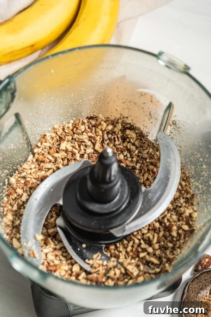 No-Bake Banana Bread Truffles 4 A food processor bowl filled with a finely blended mixture of pecans and oats, ready for the next step.