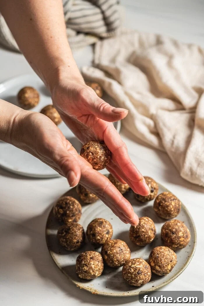 No-Bake Banana Bread Truffles 6 Two hands in action, skillfully rolling a portion of energy ball dough into a perfectly round shape.