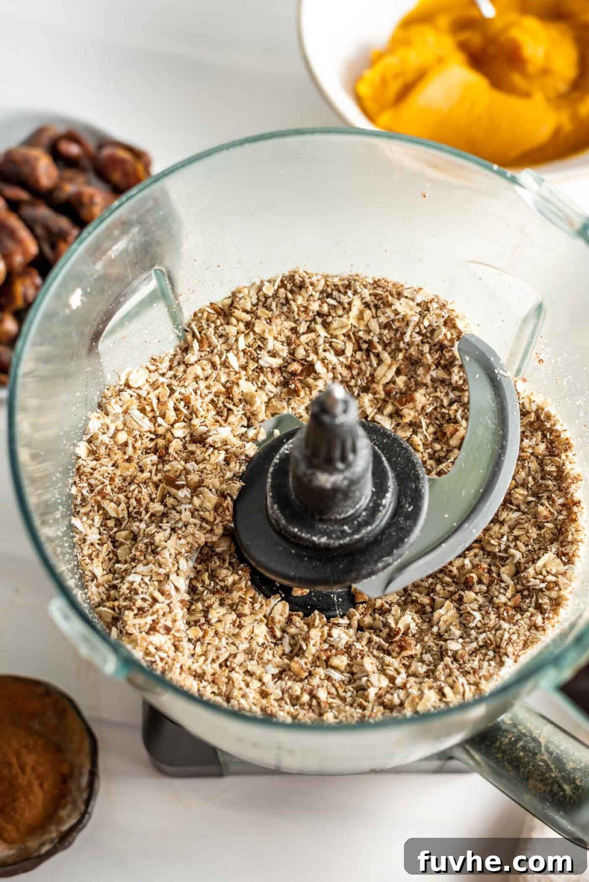 Pumpkin Spice Power Bites 4 Finely processed pecans and oats in a food processor bowl, with separate bowls of soft dates and pumpkin puree beside it, ready to be combined.