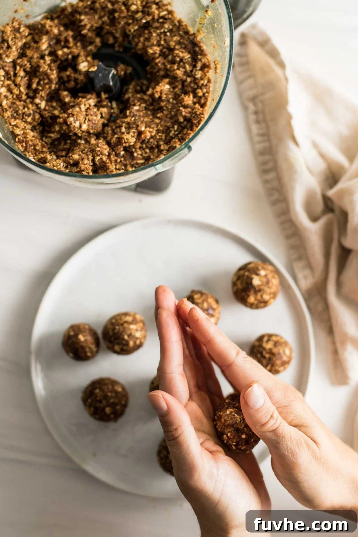 Pumpkin Spice Power Bites 6 Hands meticulously rolling the energy ball dough into perfectly round shapes, with a plate of finished balls visible below.
