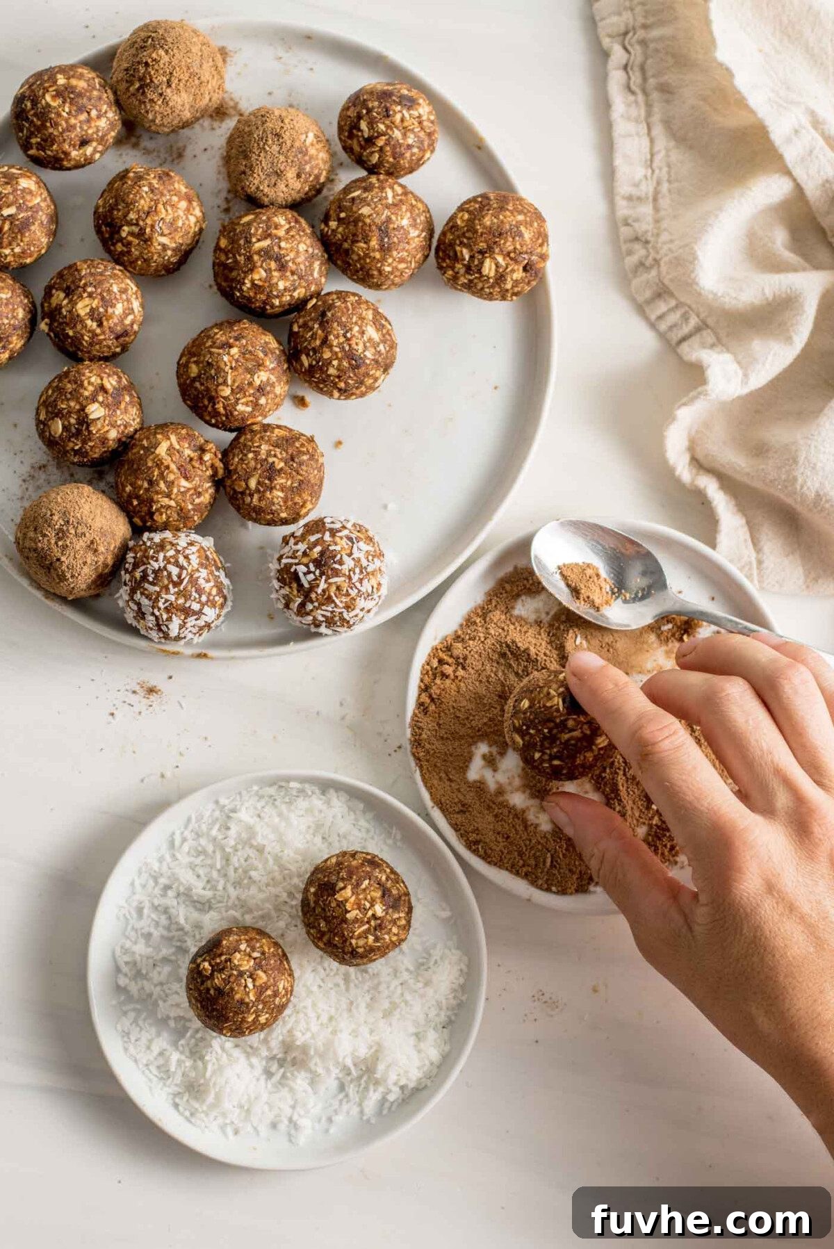 Pumpkin Spice Power Bites 7 A hand gently rolling an energy ball in a shallow dish of coconut sugar mixed with cinnamon, with more finished balls nearby.