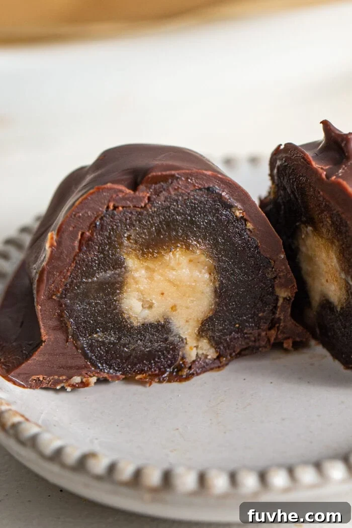 Decadent Chocolate Peanut Butter Dates 9 A close-up view of a perfectly sliced chocolate-covered Medjool date, revealing its enticing peanut butter filling, artfully presented on a small plate.