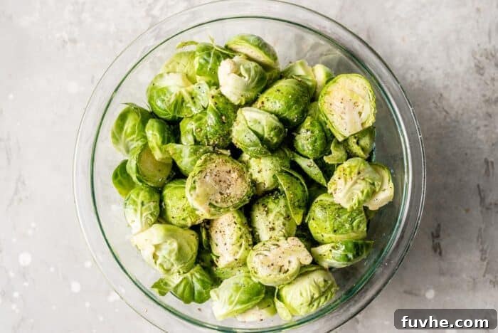 Caramelized Maple Dijon Brussels Sprouts 4 Halved Brussels sprouts in a large mixing bowl, coated with olive oil, salt, and pepper.