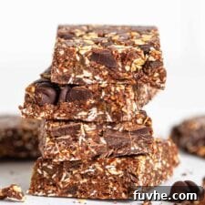 A close up of a stack of chocolate peanut butter date bars, showcasing their texture.