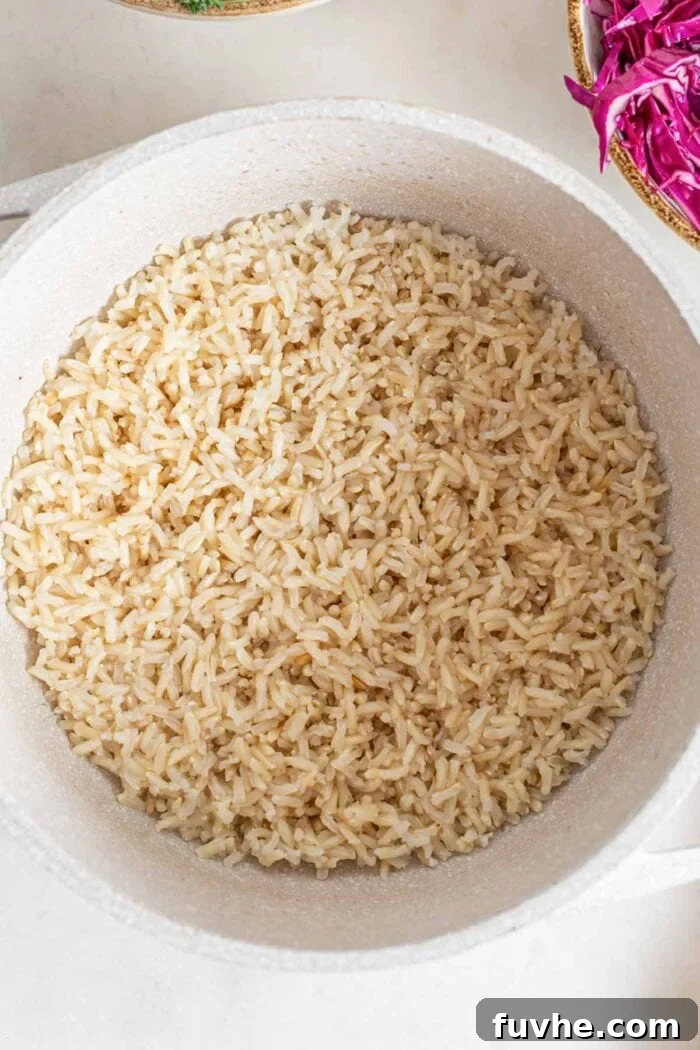 A large pot filled with freshly cooked, fluffy brown rice, ready to be incorporated into the salad or served as a hearty base.