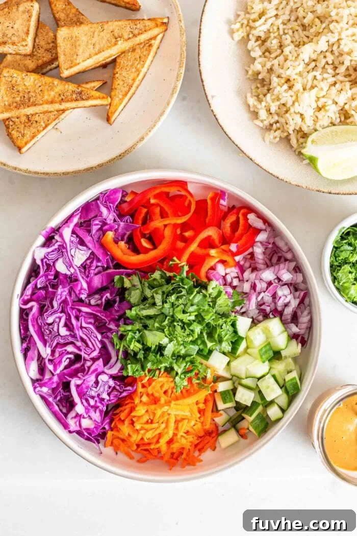 A large, inviting bowl brimming with a colorful assortment of freshly chopped cabbage, grated carrot, diced bell pepper, cucumber, and both red and green onions.