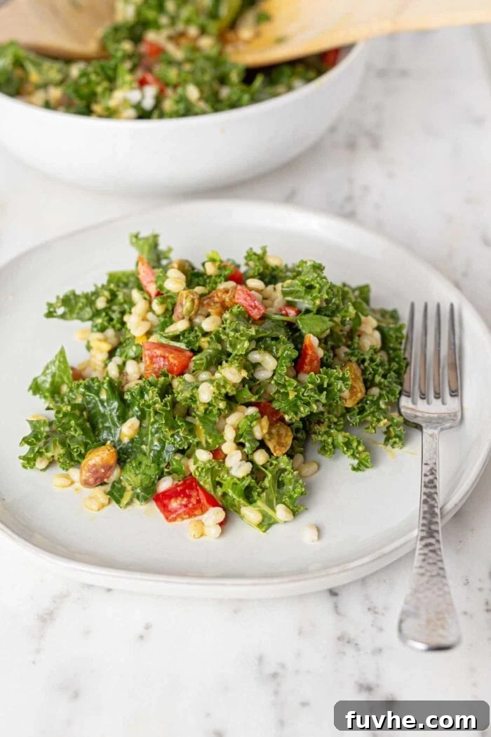 Wholesome Kale and Barley Salad 2 A beautifully arranged plate of Kale Barley Salad, featuring vibrant green kale, red bell peppers, golden barley, sweet raisins, and crunchy pistachios, all lightly dressed.