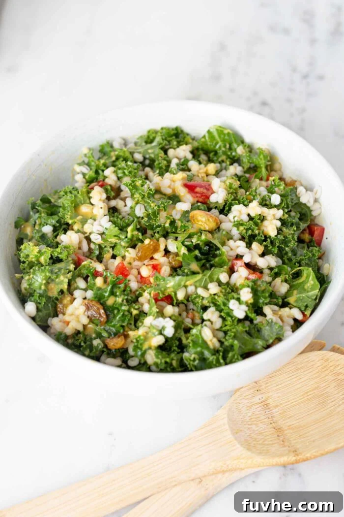 Wholesome Kale and Barley Salad 4 A large, colorful kale and barley salad filled with green kale, golden barley, red bell peppers, dark raisins, and bright green pistachios, presented in a rustic salad bowl.