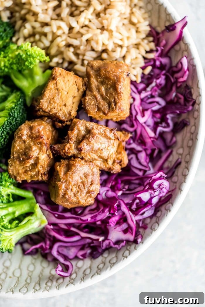 Plant-Based Macro Meal Blueprint 6 A nourishing bowl featuring marinated baked tempeh, complemented by vibrant red cabbage, crisp broccoli, and wholesome brown rice.