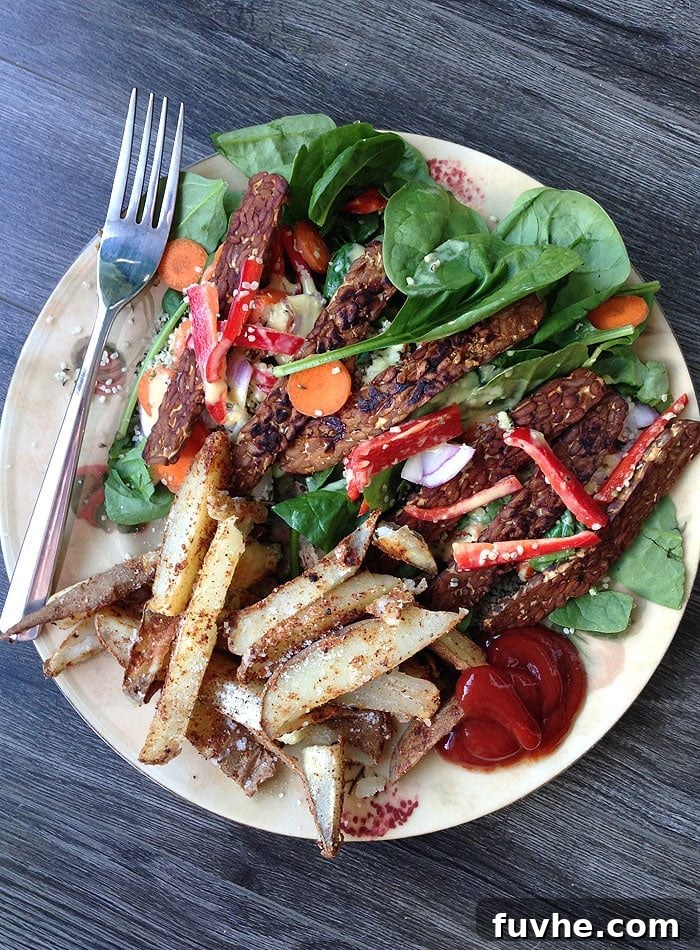 Plant-Based Macro Meal Blueprint 10 A generous plate of fresh green salad accompanied by crispy tempeh and perfectly baked potato wedges, a fulfilling vegan meal.