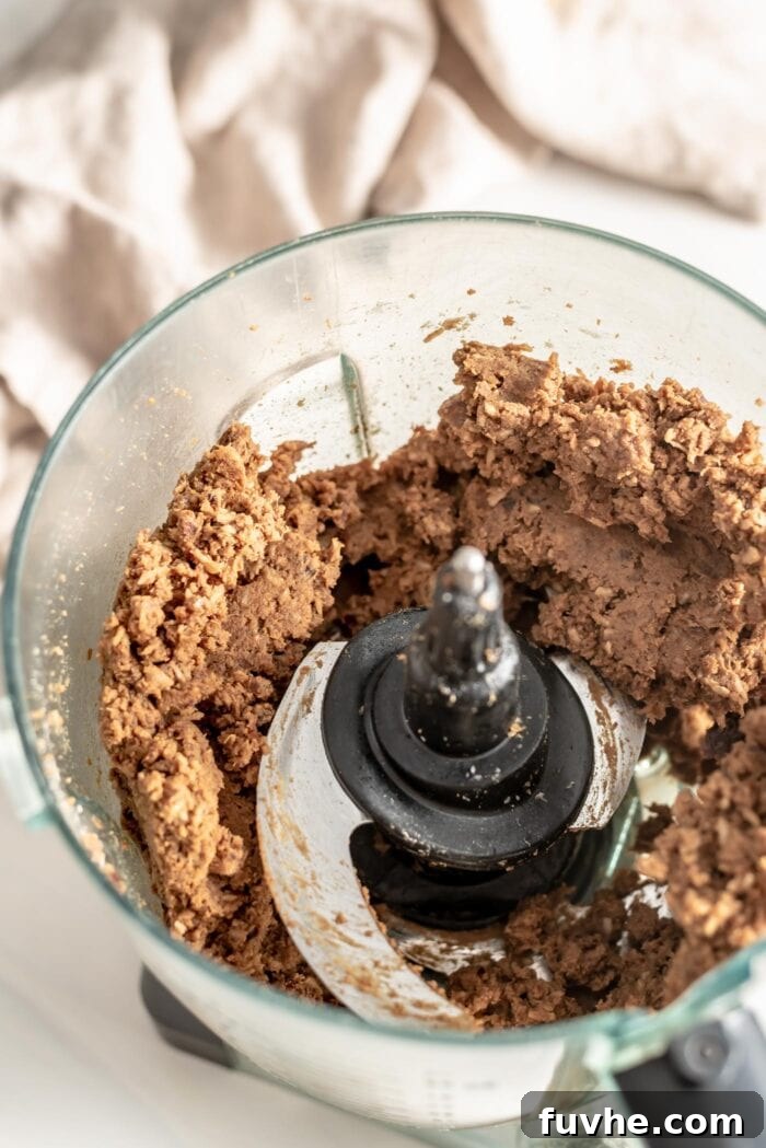 Vegan Coffee Coconut Energy Balls 5 The food processor bowl contains a thick, well-blended dough, showcasing the perfect consistency for rolling into protein balls.