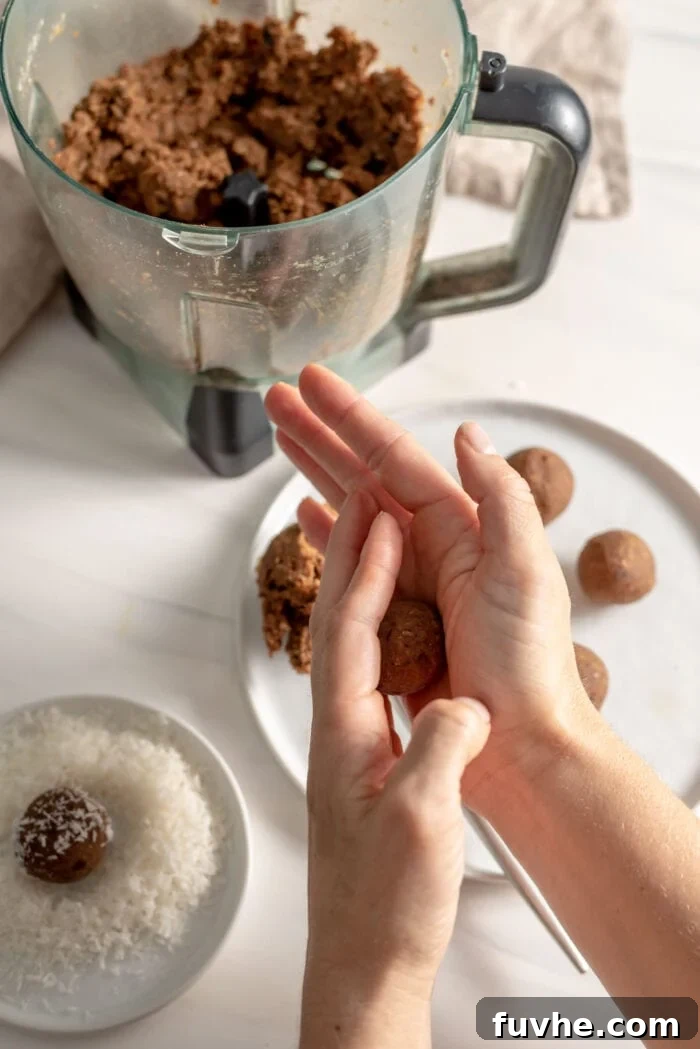 Vegan Coffee Coconut Energy Balls 6 A pair of hands gently rolling a portion of the dough into a perfectly round energy ball, demonstrating the tactile step of the recipe.
