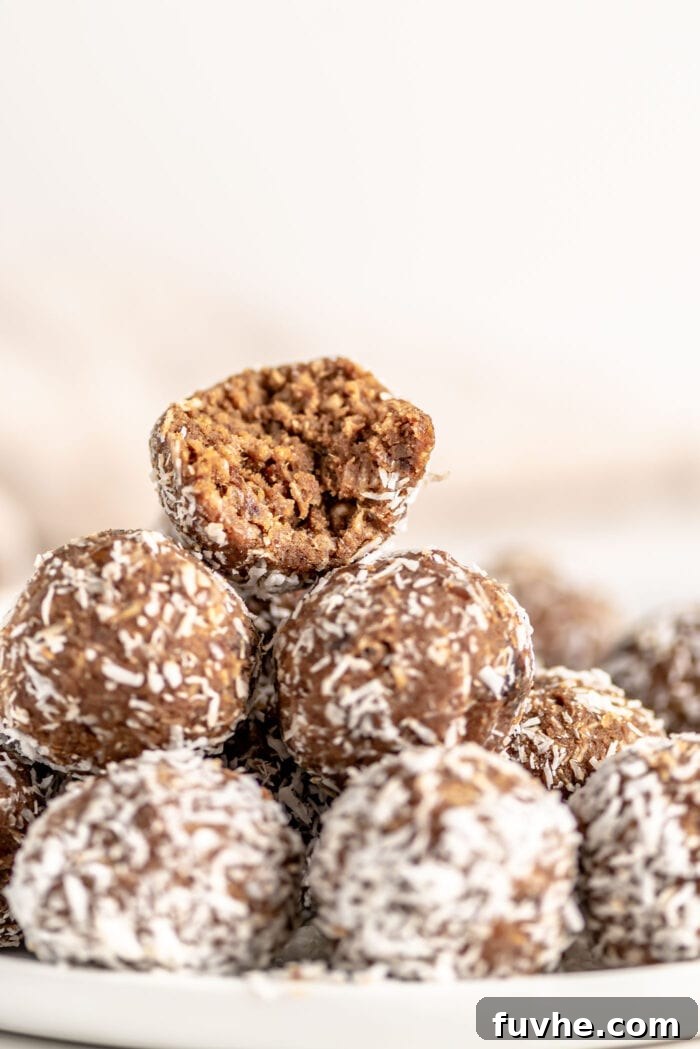 Vegan Coffee Coconut Energy Balls 7 A beautifully arranged stack of finished energy balls on a plate, with one ball on top showing a delightful bite taken out, revealing its rich interior.