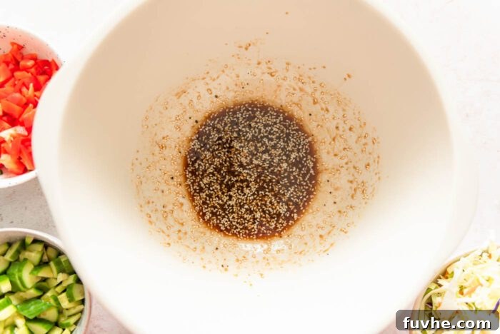 A soy ginger sesame dressing with sesame seeds in a large salad bowl.