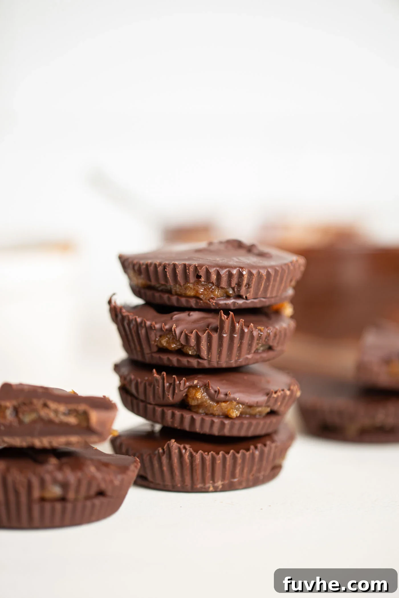 A stack of luscious vegan chocolate caramel cups, showcasing their rich chocolate exterior and inviting caramel filling.