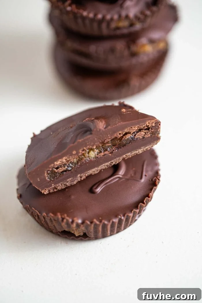 A perfectly halved vegan chocolate caramel cup, revealing its luscious, golden caramel center nestled within the rich chocolate shell.