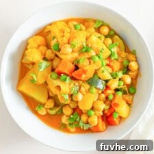 Golden Chickpea Potato Curry 8 Close up image of a bowl of delicious vegan chickpea potato curry, garnished with fresh herbs.
