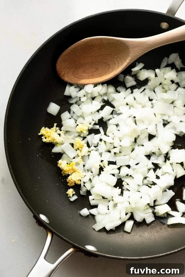 Cooking onions and garlic in a sauce pan for coconut ginger carrot soup.