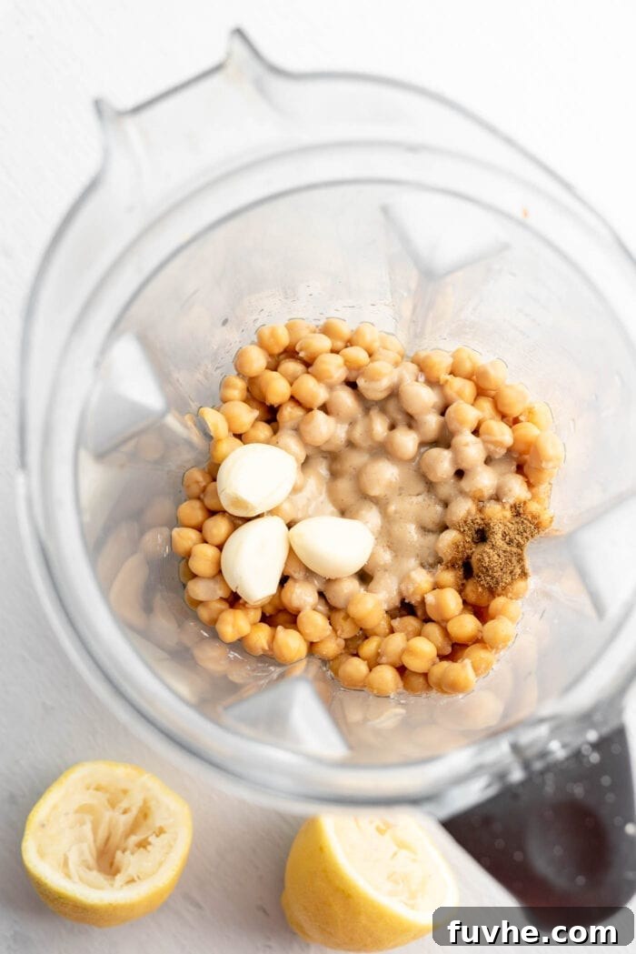 The process of blending the base hummus ingredients in a food processor, showcasing the creamy texture beginning to form before the roasted carrots are added.
