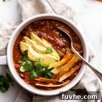 Bowl of tortilla soup topped with avocado, cilantro and tortilla strips.