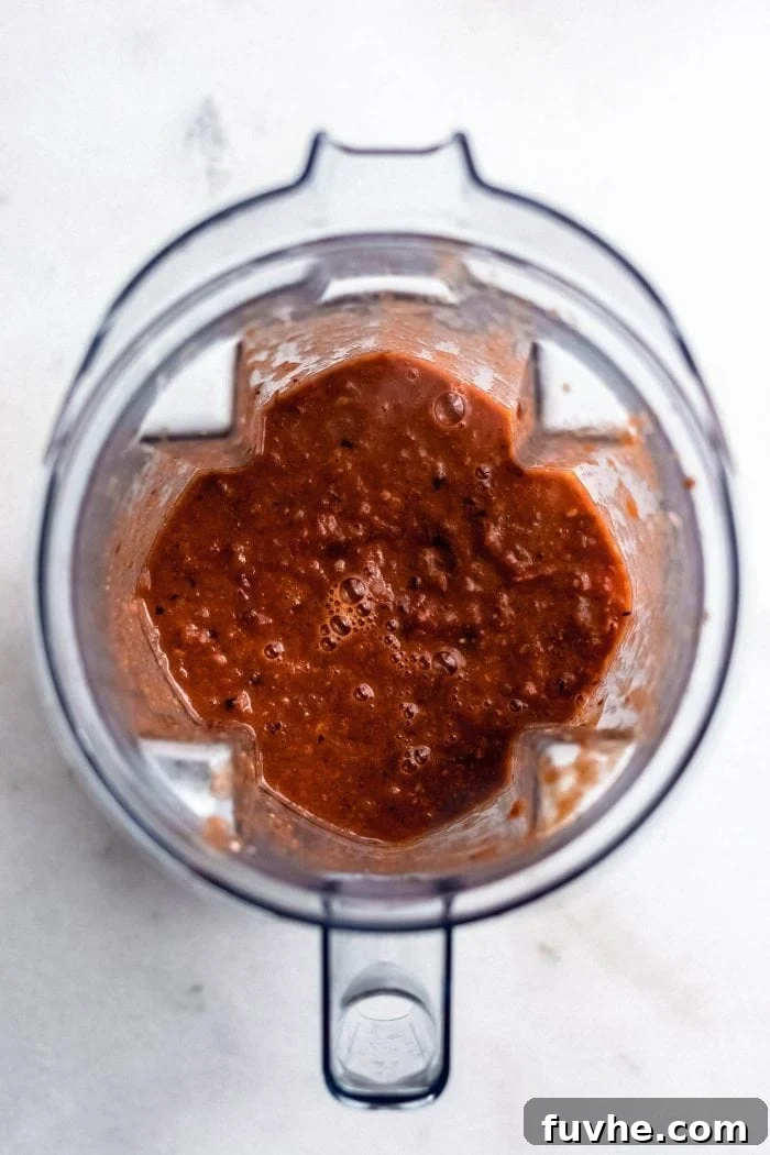 Vegan tortilla soup being blended in a stand blender, transforming into a smoother consistency while retaining some texture.