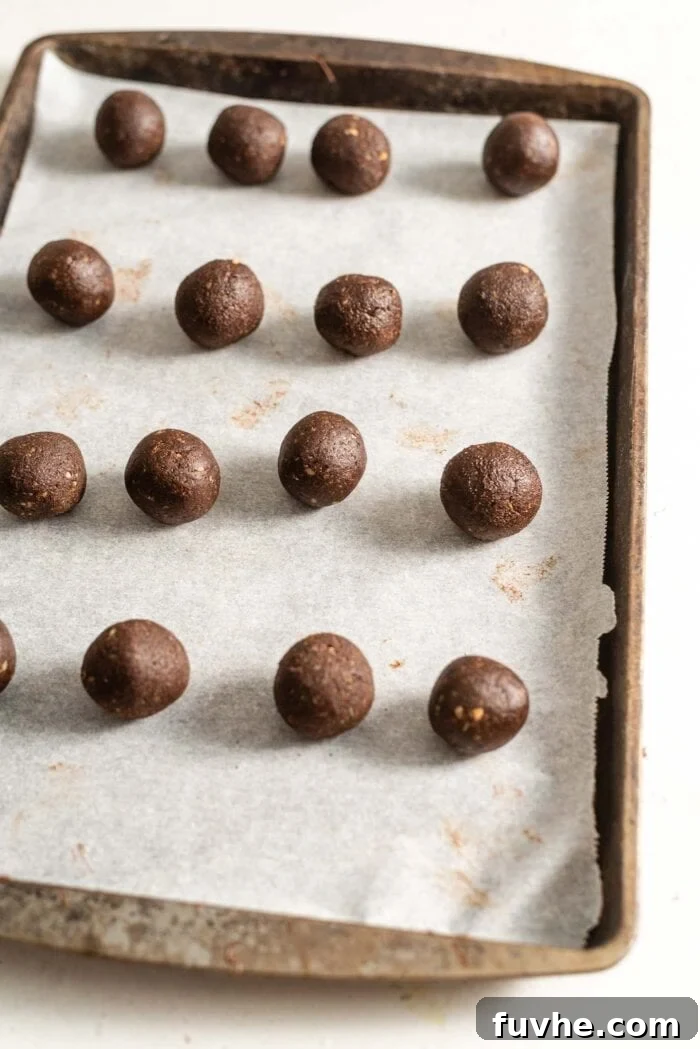 Salty Sweet Vegan Chocolate Truffles 5 Sixteen perfectly rolled chocolate truffles arranged on a baking tray lined with parchment paper, ready for coating.