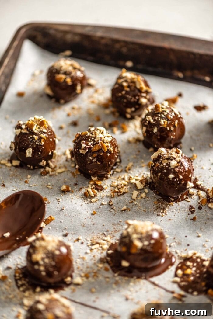 Salty Sweet Vegan Chocolate Truffles 7 Freshly chocolate-covered truffles, generously sprinkled with crushed pretzels, cooling on a parchment-lined baking tray.