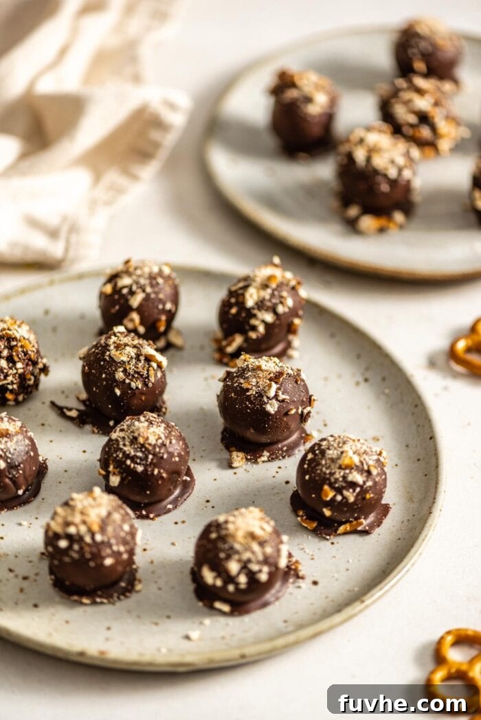 Salty Sweet Vegan Chocolate Truffles 8 A plate brimming with perfectly crafted chocolate truffles, generously sprinkled with crushed pretzels, ready to be served.