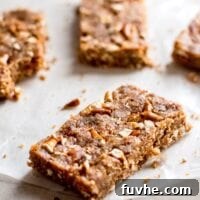 A no-bake pretzel granola bar sitting on a piece of parchment paper. There are more bars in the background.