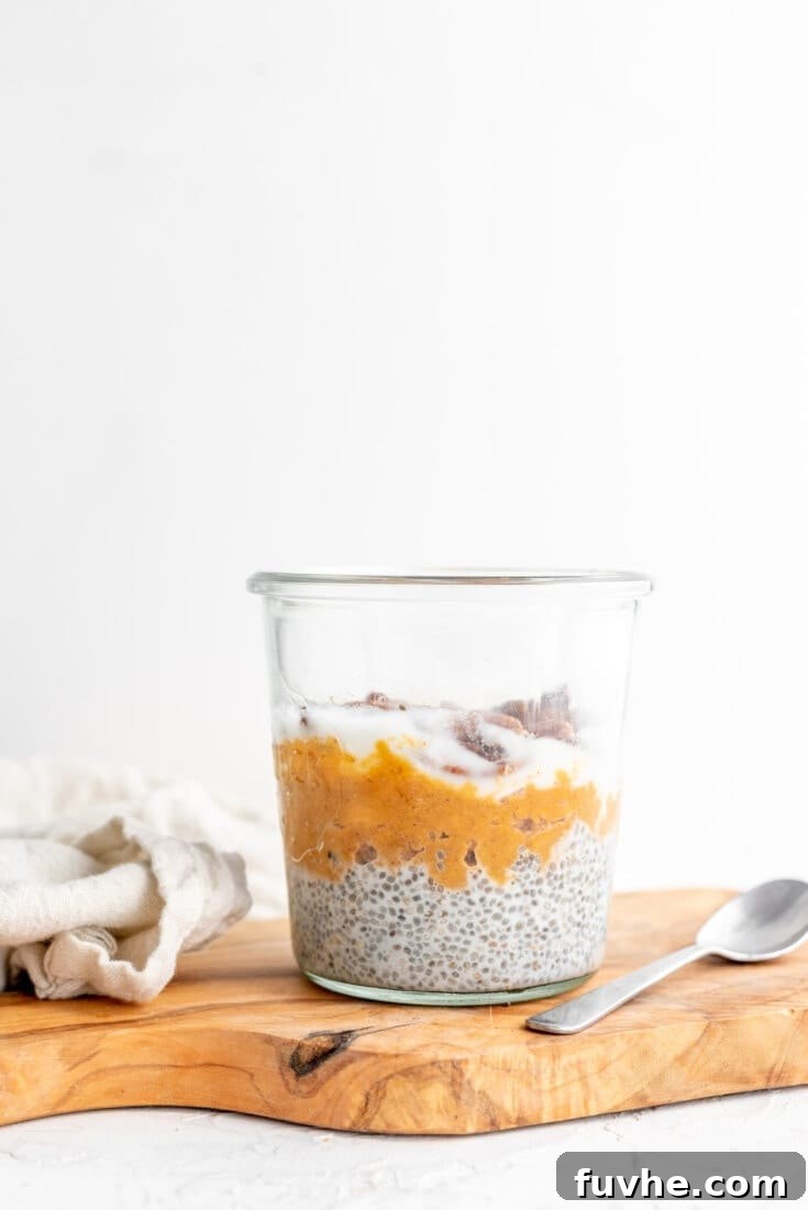 A glass jar filled with layered sweet potato chia seed pudding, topped with a sprinkle of cinnamon, perfect for a warming breakfast.