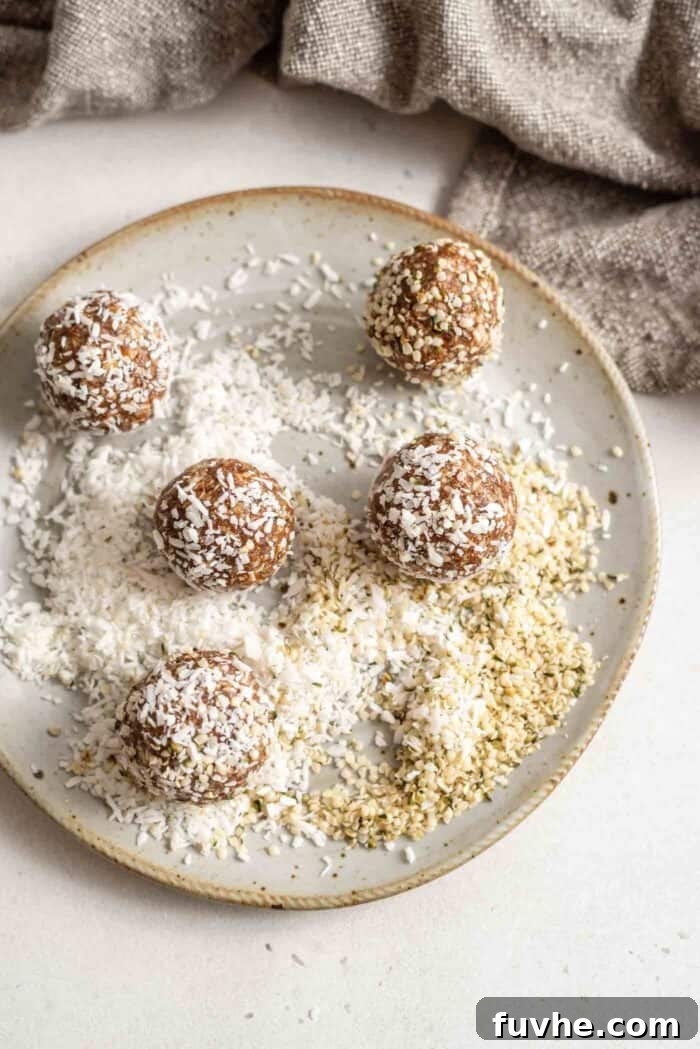 Hands rolling energy balls in a mixture of shredded coconut and hemp seeds on a plate.