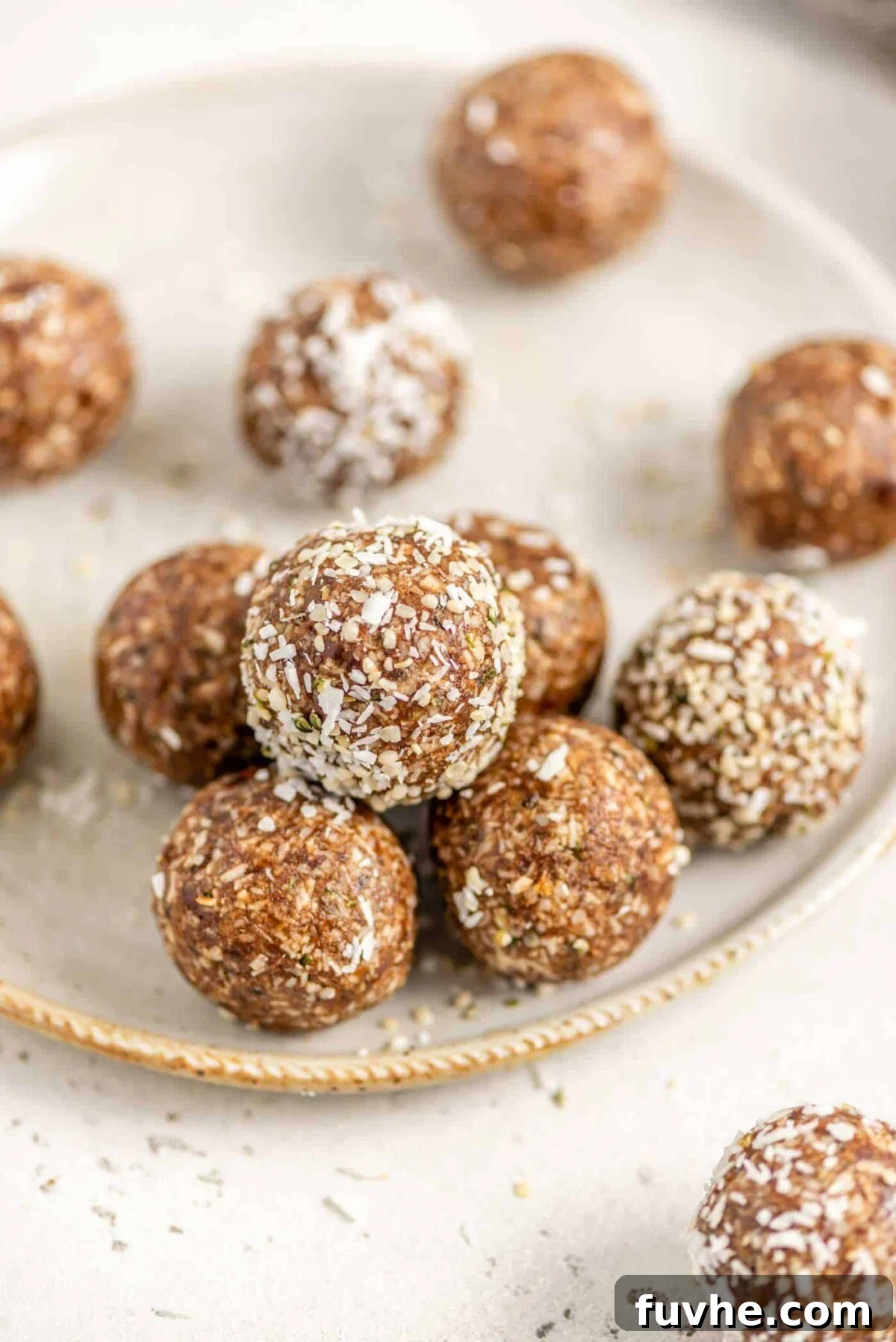A close-up shot of energy balls generously coated in shredded coconut, artfully arranged on a plate.