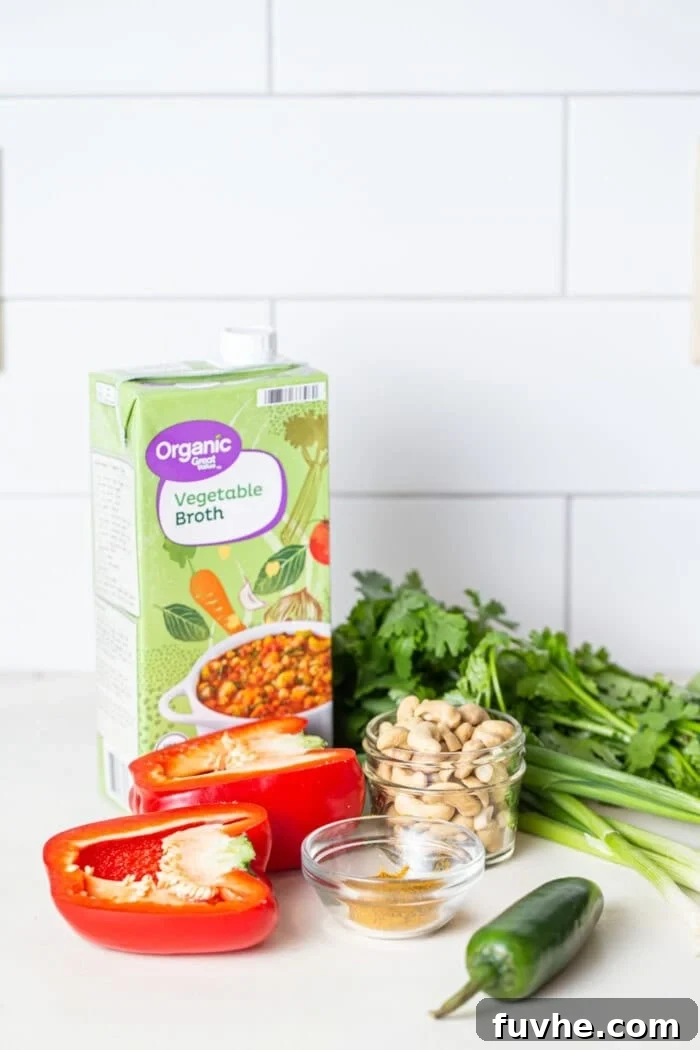Crispy Cashew Tofu Fried Rice 3 A carton of vegetable broth, a bowl of raw cashews, a vibrant red bell pepper, and a fresh jalapeño neatly arranged on a kitchen counter, ready for cooking.