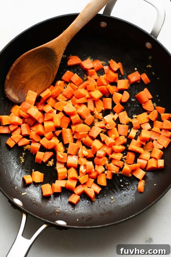 Plant-Based Cauliflower Fried Rice 6 Diced carrots cooking in a skillet with sautéed aromatics, softening before the rest of the ingredients are incorporated into the delicious fried cauliflower rice.